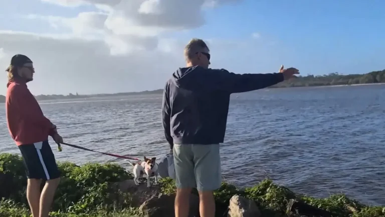 Two men and a dog enjoying a quiet riverside walk along the water on the Far North Coast.